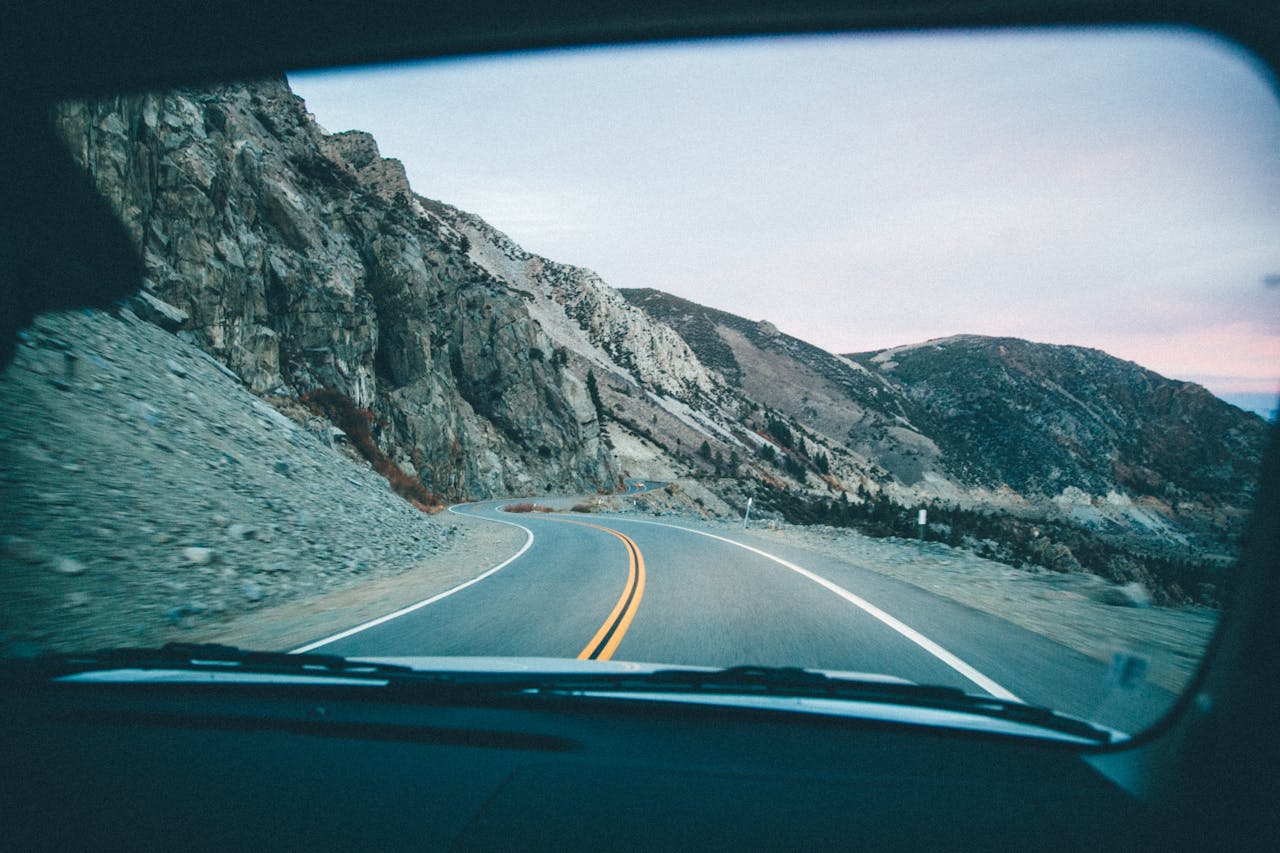creative View of a winding mountain road through a car windshield during a road trip.